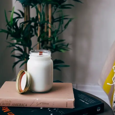 Bougie dans un pot en verre posée sur des livres