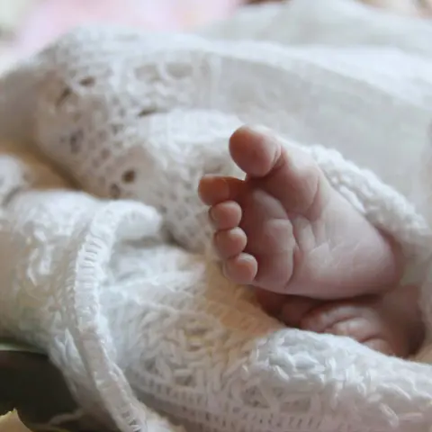 Pied de bébé sous une couverture en tricot blanc