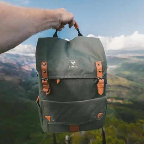 Sac à dos vert kaki tenu à bout de bras